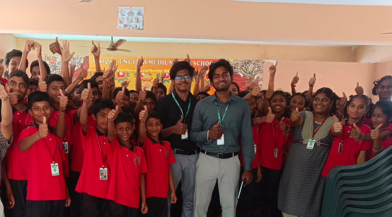Founders with students at Unique English Medium High School during an AI session — the whole class celebrating with thumbs up.
